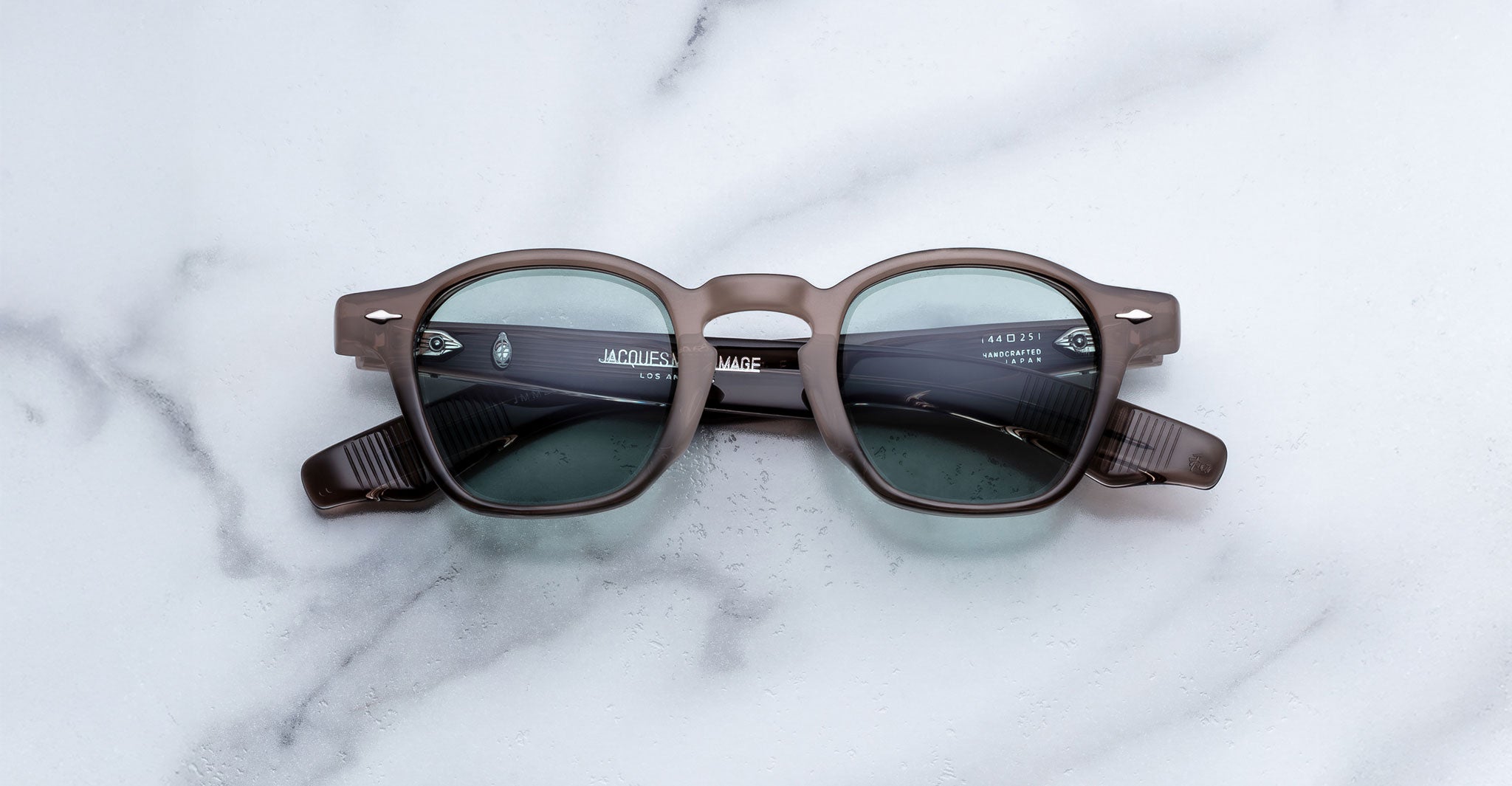 Jacques Marie Mage Zephirin in Dusty Jade round, dark-framed sunglasses with tinted lenses, front view on a flat surface.