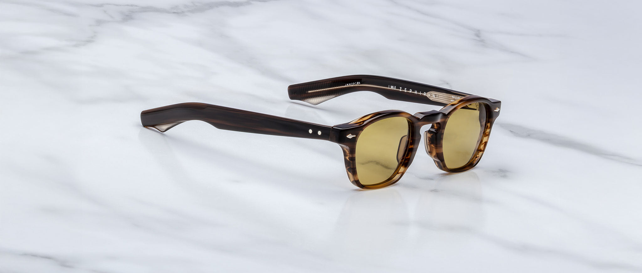 Jacques Marie Mage Zephirin sunglasses, featuring brown tortoiseshell acetate frames and round yellow-tinted lenses, rest on white marble—a limited edition piece for discerning collectors.