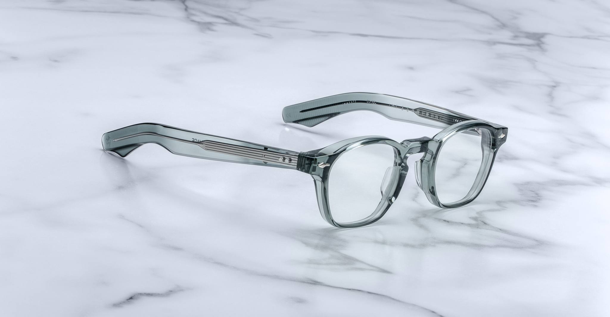 The Jacques Marie Mage Zephirin, handcrafted acetate spectacles with round lenses and thick arms, rest on a white marble surface—a refined piece from the exclusive Jacques Marie Mage collection.