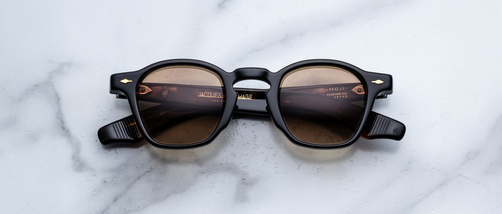 Jacques Marie Mage Zephirin in Noir 15 black round sunglasses with brown tinted lenses, top view, shown on white marble.