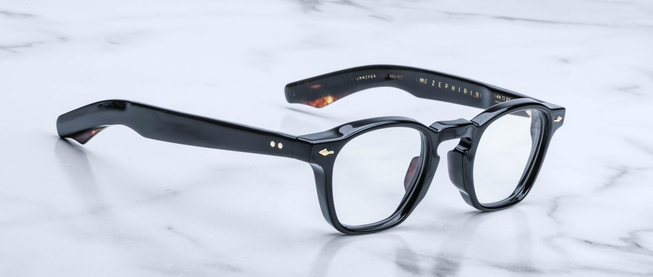A pair of Jacques Marie Mage Zephirin rectangular eyeglasses with clear lenses, handcrafted in acetate, rests elegantly on a white marble surface.