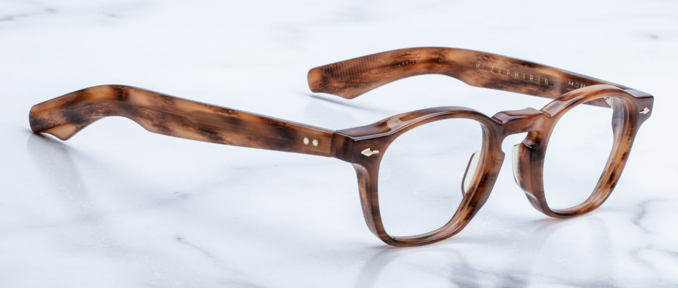 The Jacques Marie Mage Zephirin, handcrafted brown tortoiseshell acetate spectacles with round lenses, rests on a white marble surface.