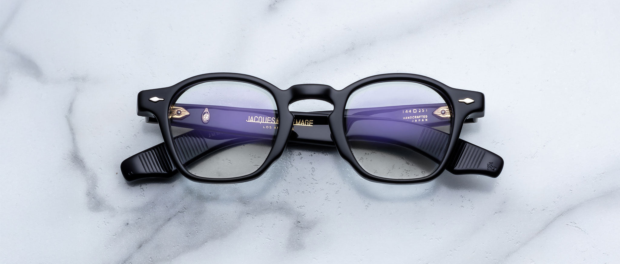 Jacques Marie Mage Zephirin in Obscure colorway round eyeglasses with black frames and purple anti-reflective lenses, top view.