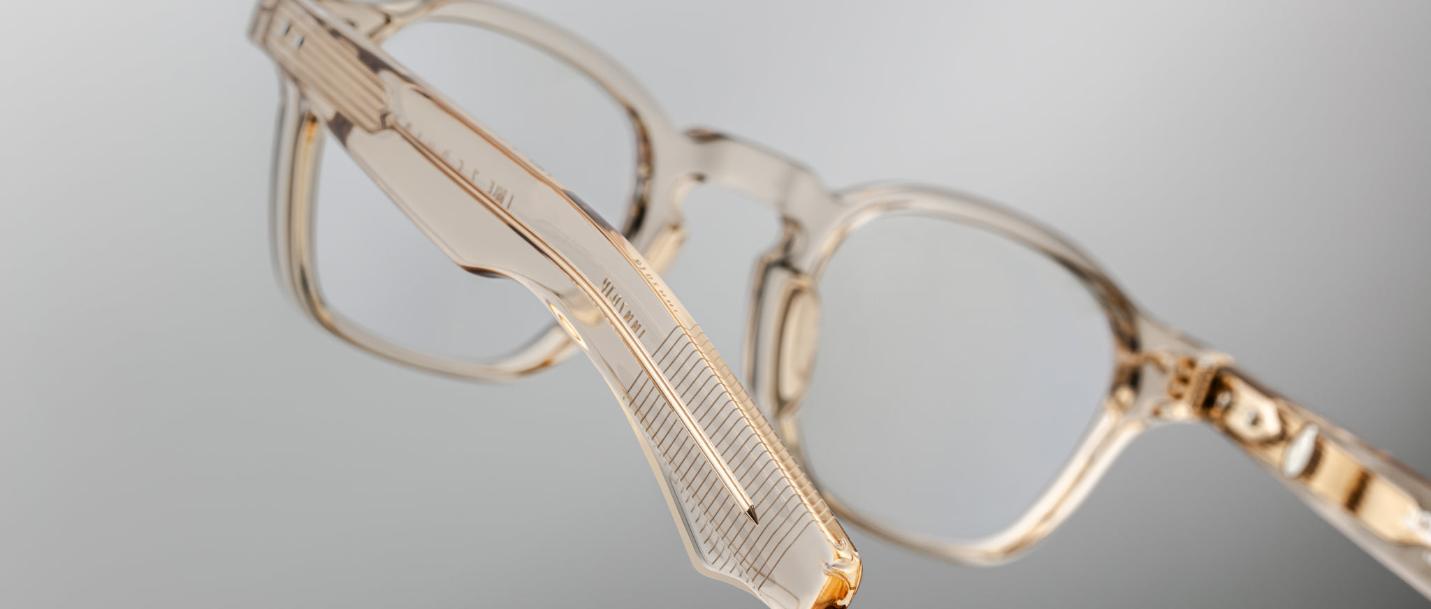 Close-up of Jacques Marie Mage Zephirin transparent beige acetate spectacles, highlighting the handcrafted side arm and hinge, inspired by the iconic limited edition eyewear style, set against a neutral background.