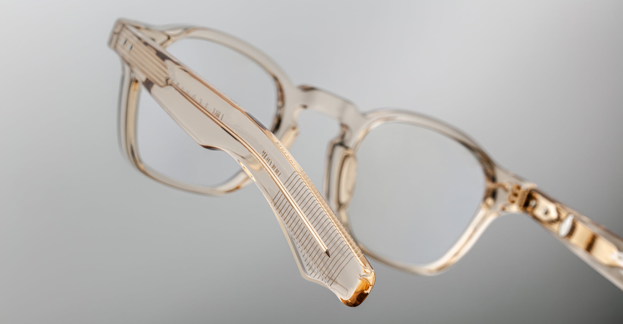 Close-up of Jacques Marie Mage Zephirin transparent beige acetate spectacles, highlighting the handcrafted side arm and hinge, inspired by the iconic limited edition eyewear style, set against a neutral background.