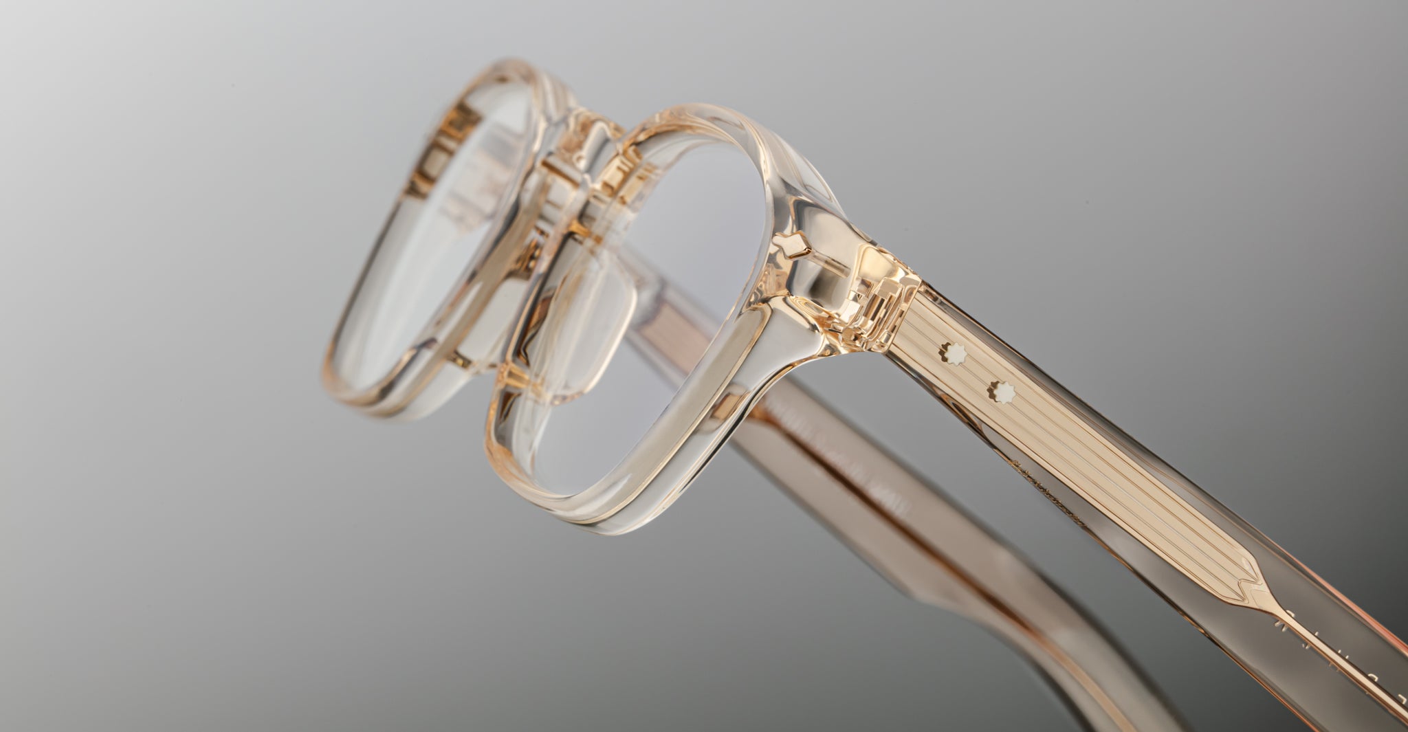Close-up of Jacques Marie Mage Zephirin eyeglasses featuring transparent beige handcrafted acetate frames, rectangular lenses, and a minimalist design, set against a plain gradient background.