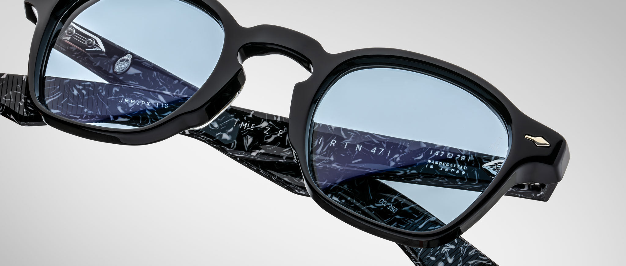 Close-up of Jacques Marie Mage Zephirin eyeglasses, featuring black frames, blue lenses, and patterned temples, crafted from premium handcrafted acetate and shown against a plain background.