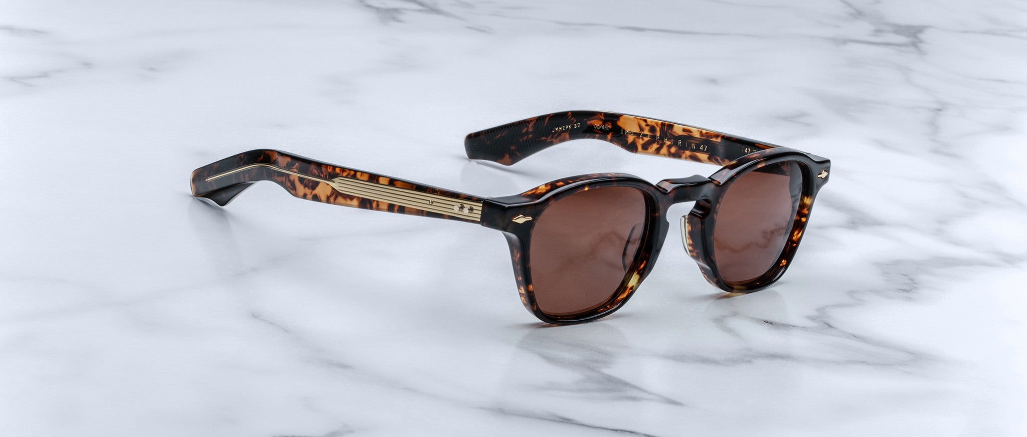 Jacques Marie Mage Zephirin 47 sunglasses, featuring brown lenses and gold accents, shown from above.
