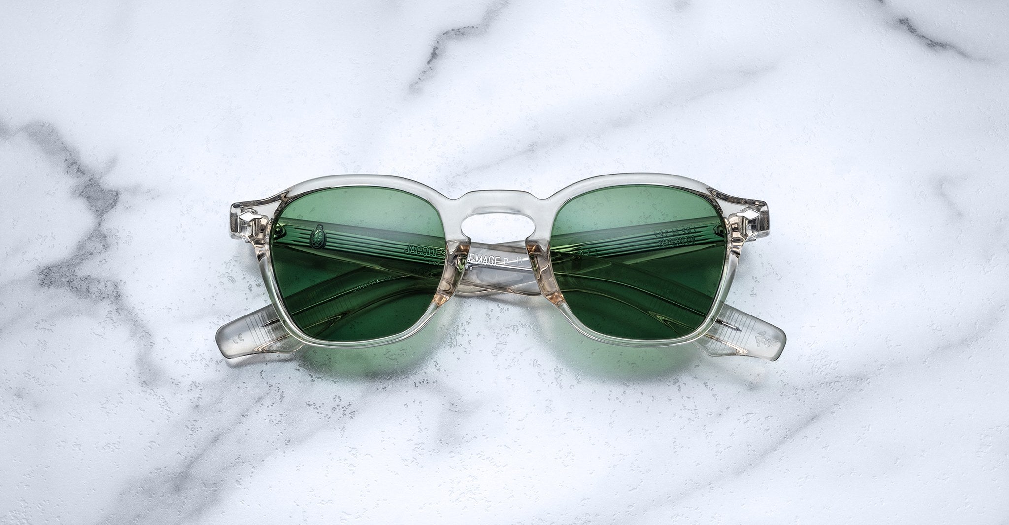 Jacques Marie Mage Zephirin 47 sunglasses with clear frames and green lenses shown from above.