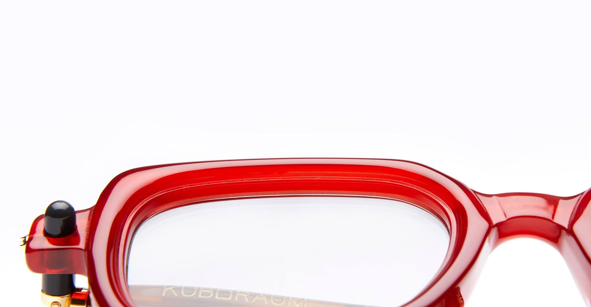 Close-up of Kuboraum P4 RED rectangular eyeglasses with clear lenses, showing the left side of the frame and part of the black temple arm, set against a plain white background.
