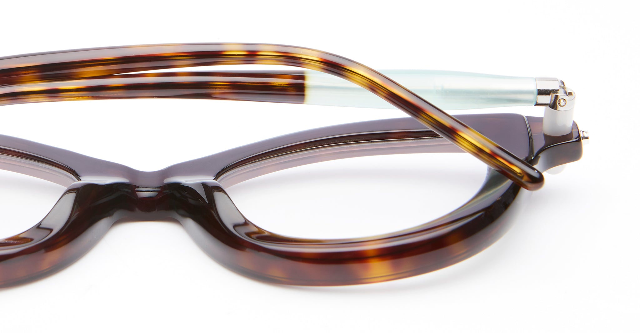 Close-up of a pair of tortoiseshell eyeglasses with one temple arm folded over the frame, set against a white background.