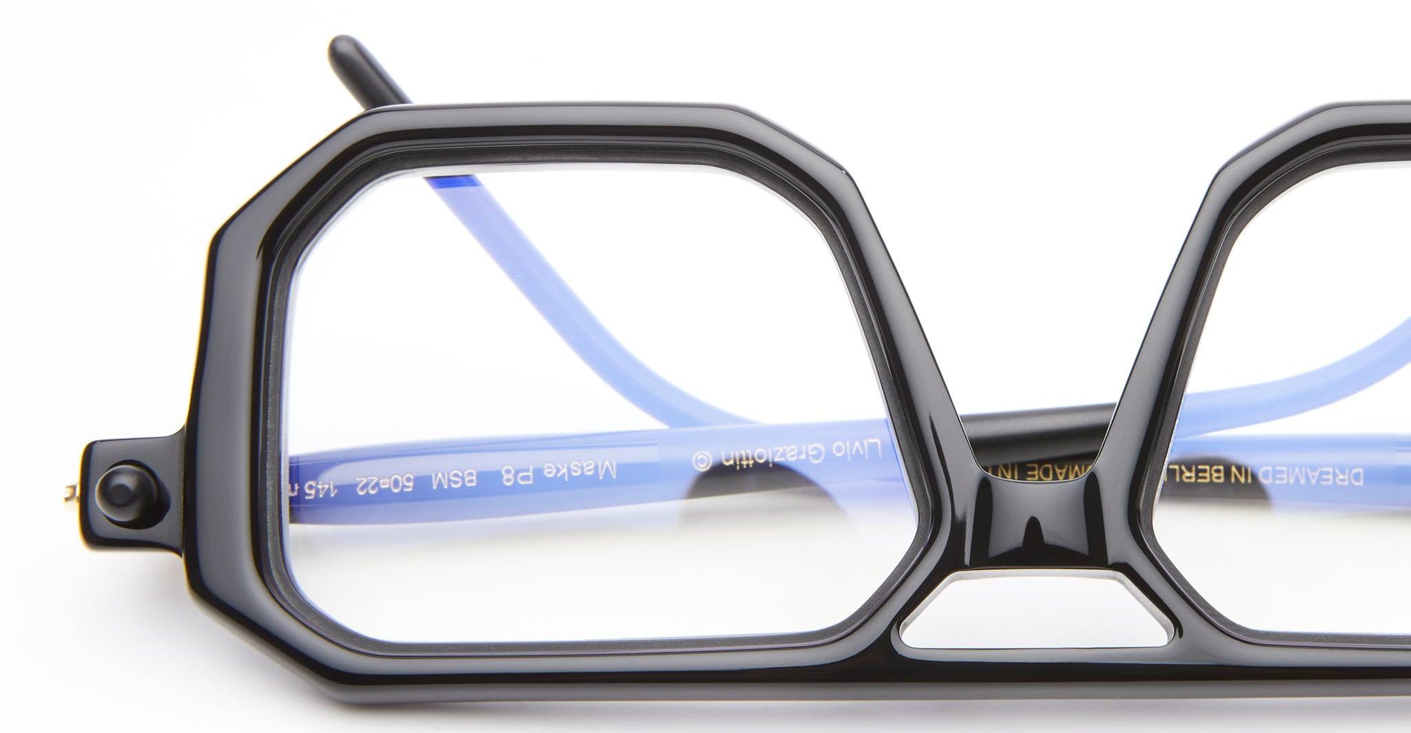 Close-up of KUBORAUM P8 eyeglasses, featuring black geometric frames and blue temples, angled for a detailed product view.