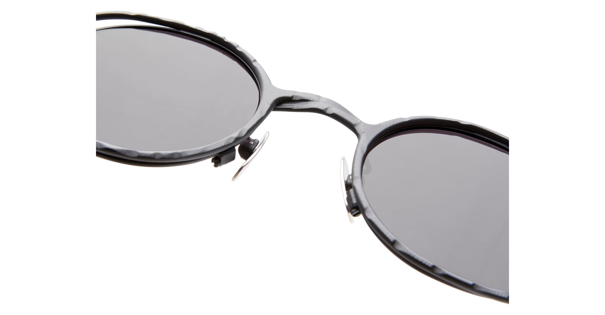 Close-up of Kuboraum H11 round black sunglasses with dark lenses, metal nose pads, and a textured frame, set against a white background.