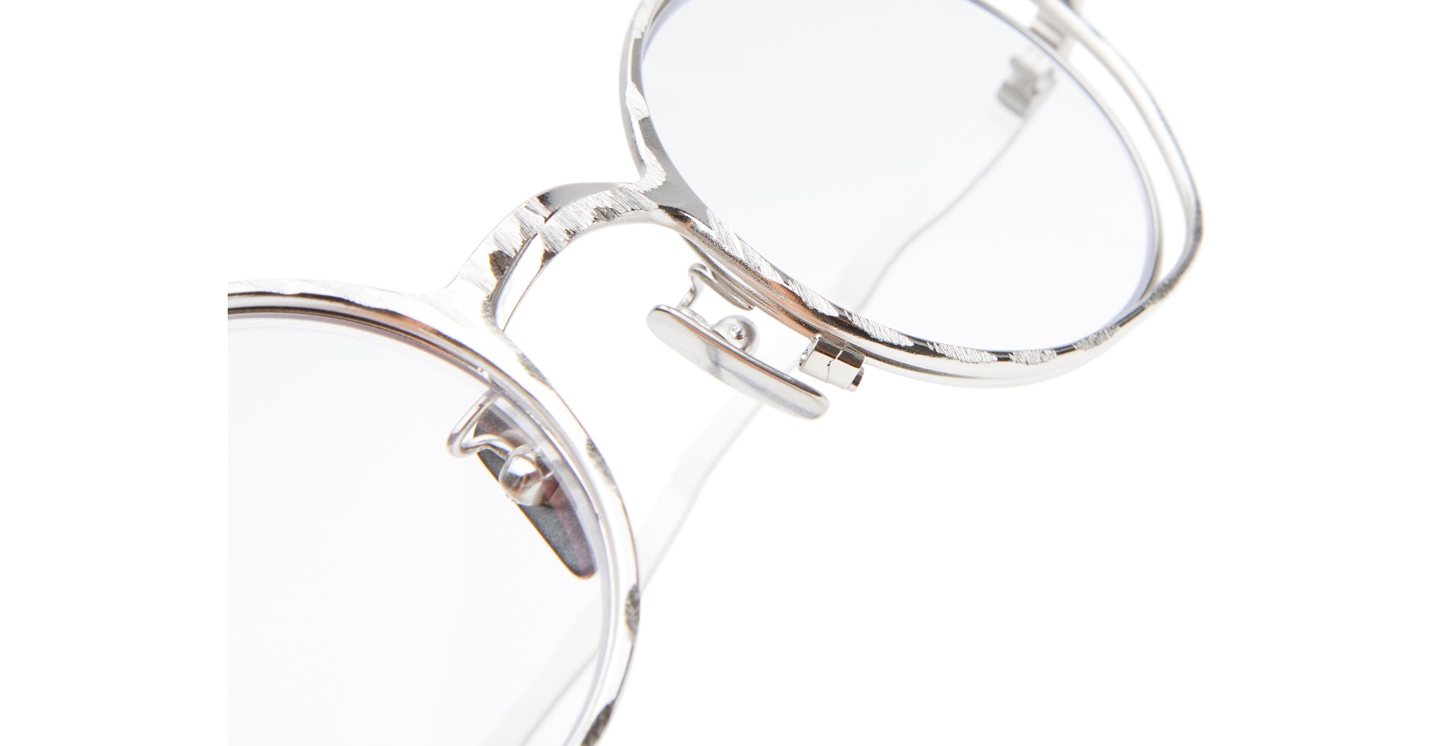 Close-up of Kuboraum H11 round silver metal eyeglasses with clear lenses, highlighting the detailed frame texture and adjustable nose pads. The mostly white background emphasizes the right half of the glasses.