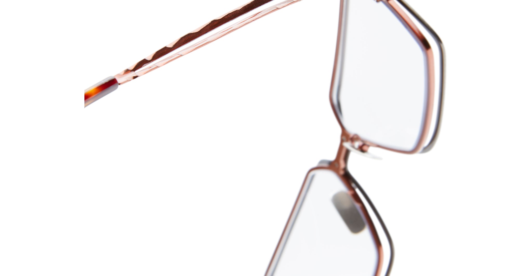 Close-up of the Kuboraum H15 eyeglasses featuring rose gold frames and clear lenses, displayed at an angle on a white background.