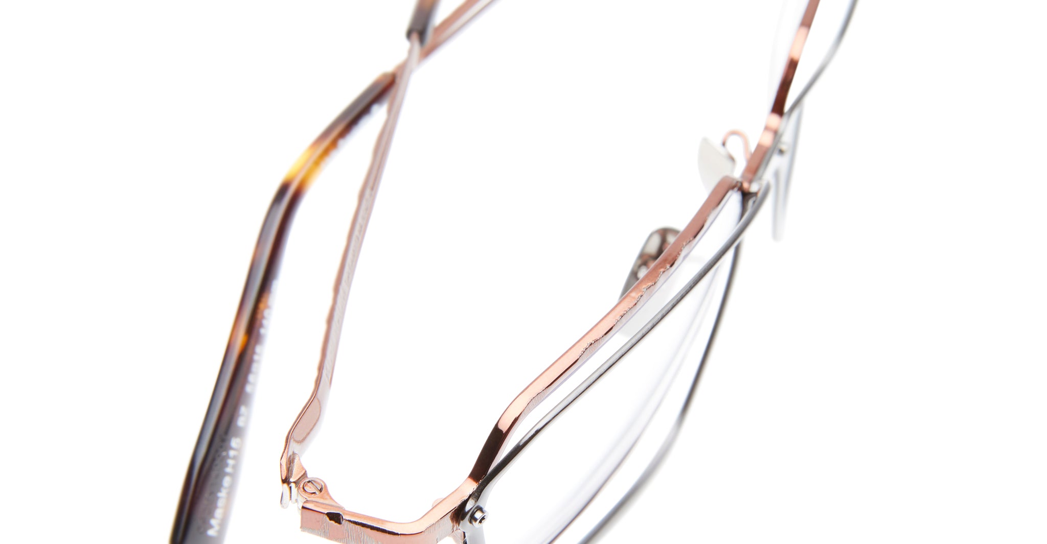 Close-up of Kuboraum H15 eyeglasses featuring thin rose gold metal frames and tortoiseshell-patterned arms, displayed on a white background.