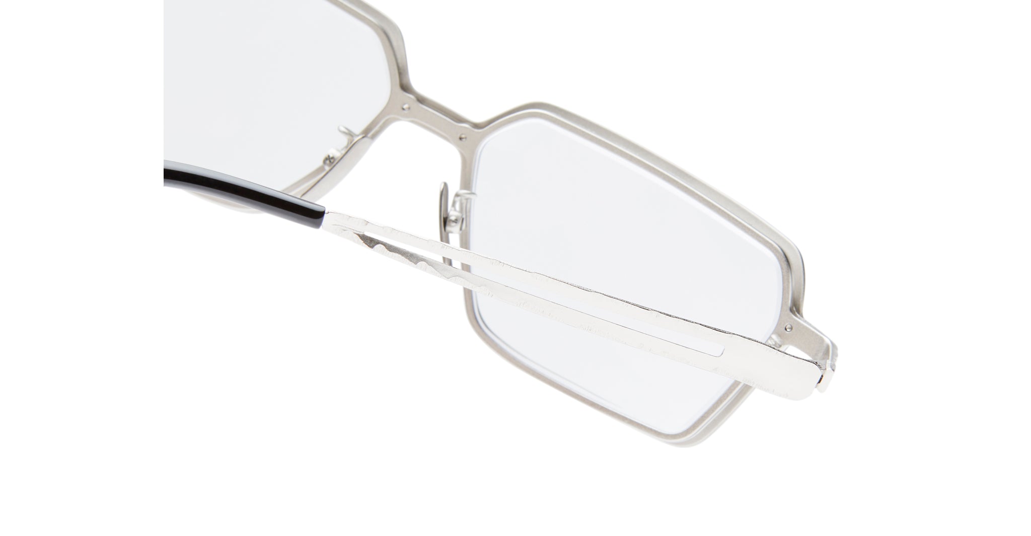 Close-up of the temple and corner of Kuboraum H15 silver metal eyeglasses with rectangular lenses and clear nose pads, set against a white background.