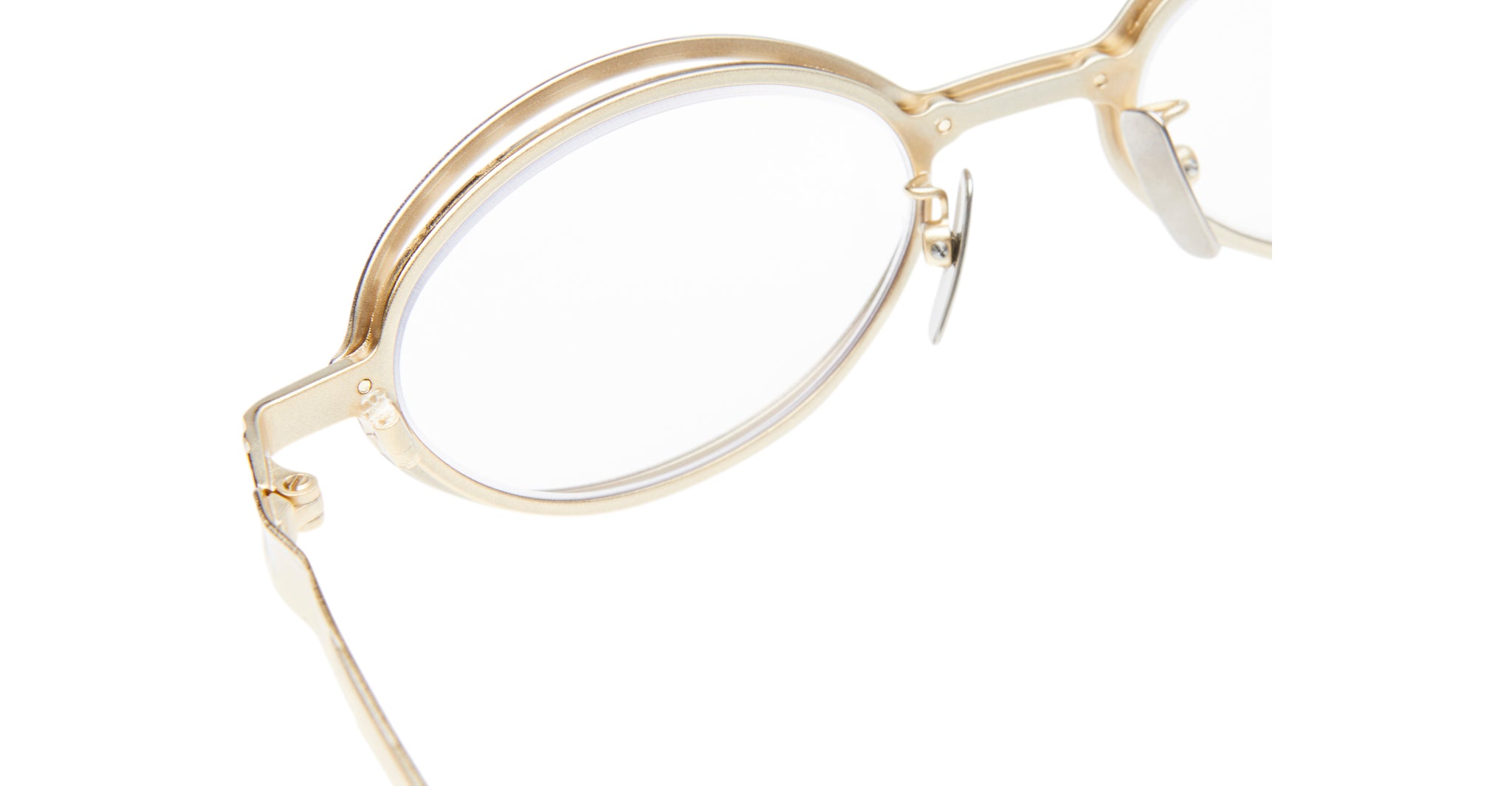Close-up of Kuboraum H18 gold-rimmed round eyeglasses with clear lenses, highlighting the frame, nose pads, and left temple against a white background.