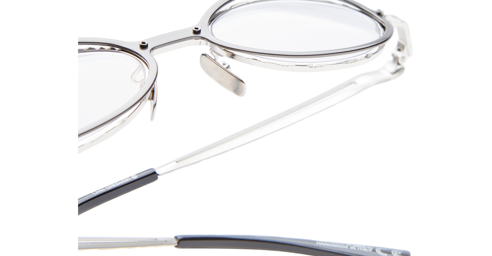 Close-up of Kuboraum H18 silver-framed eyeglasses with clear lenses, highlighting the nose pad, detailed frame, and part of the temple arms against a white background.