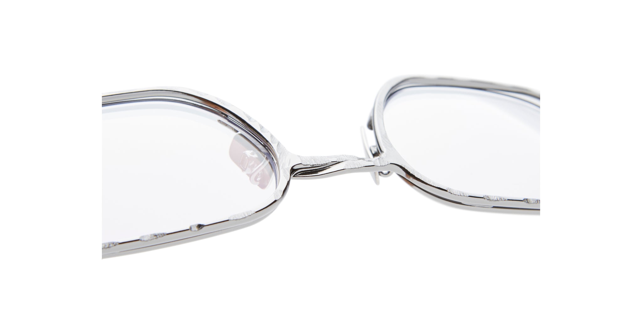 Close-up of Kuboraum H22 eyeglasses featuring silver metal frames and clear lenses, highlighting the bridge and nose pads.