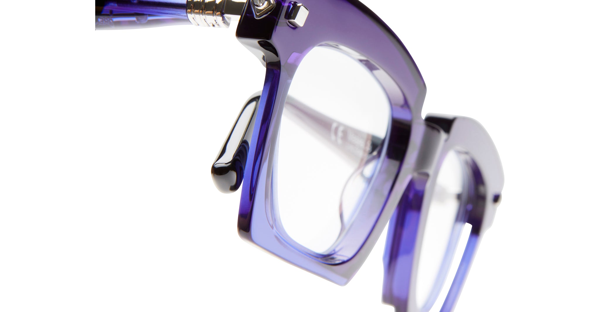 Close-up view of Kuboraum J9 eyeglasses featuring thick, translucent purple frames, with emphasis on the left lens and hinge against a white background.
