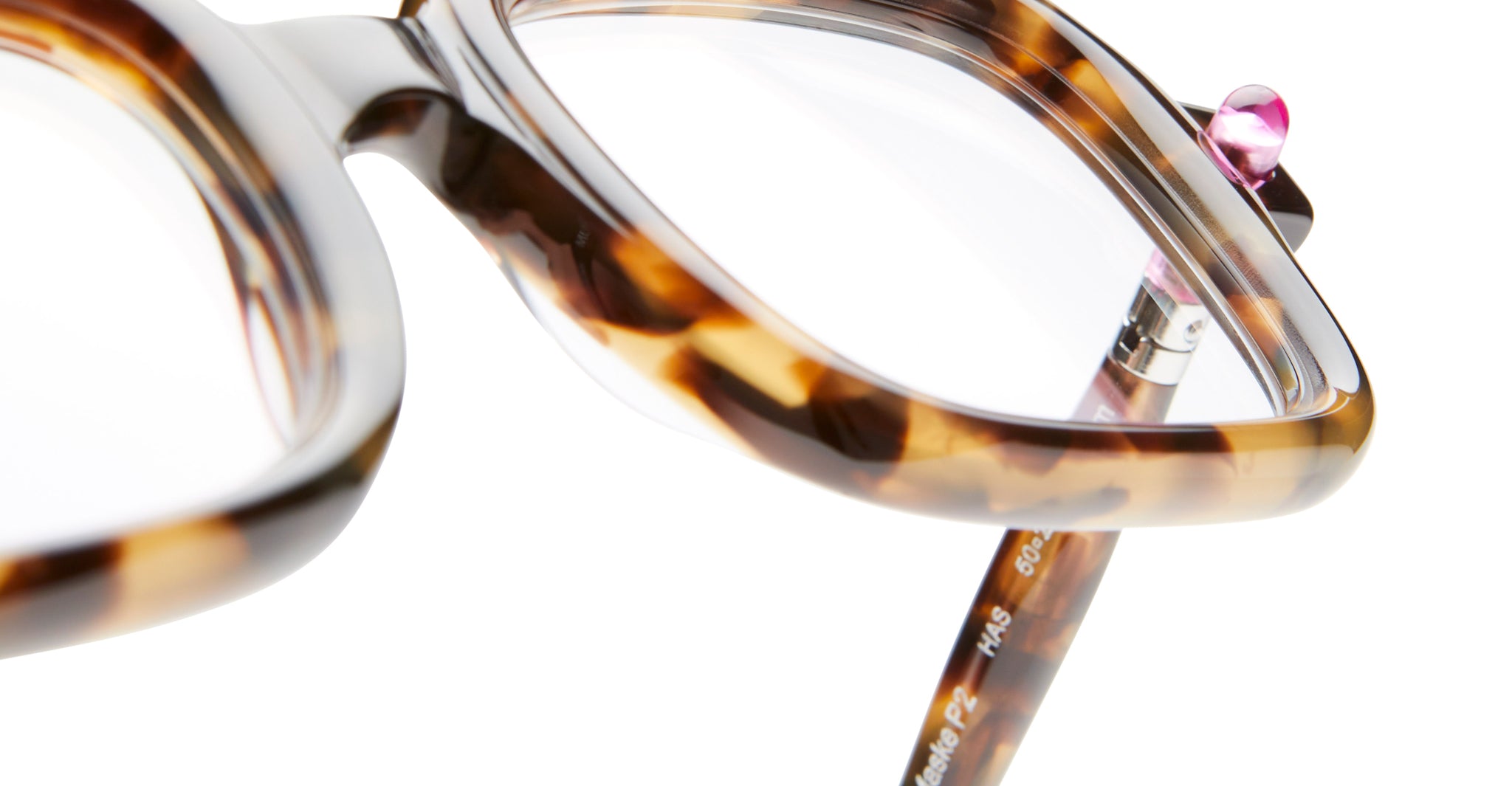 Close-up of Kuboraum P2 tortoiseshell square eyeglass frames featuring a pink stud detail on the top corner, set against a white background.