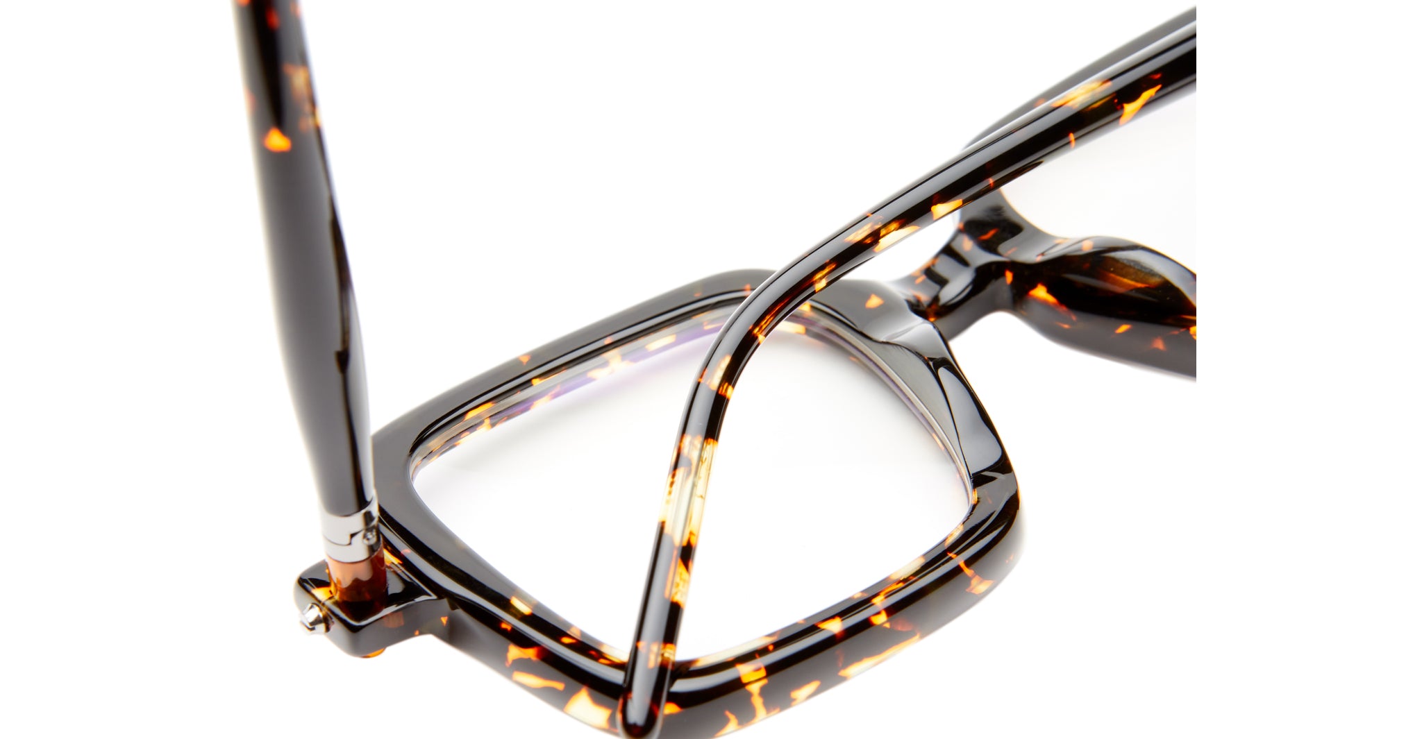 Close-up of Kuboraum P21 tortoiseshell eyeglass frames with rectangular lenses. One arm is folded, the other partially extended, showcasing their glossy, speckled brown and amber pattern against a white background.