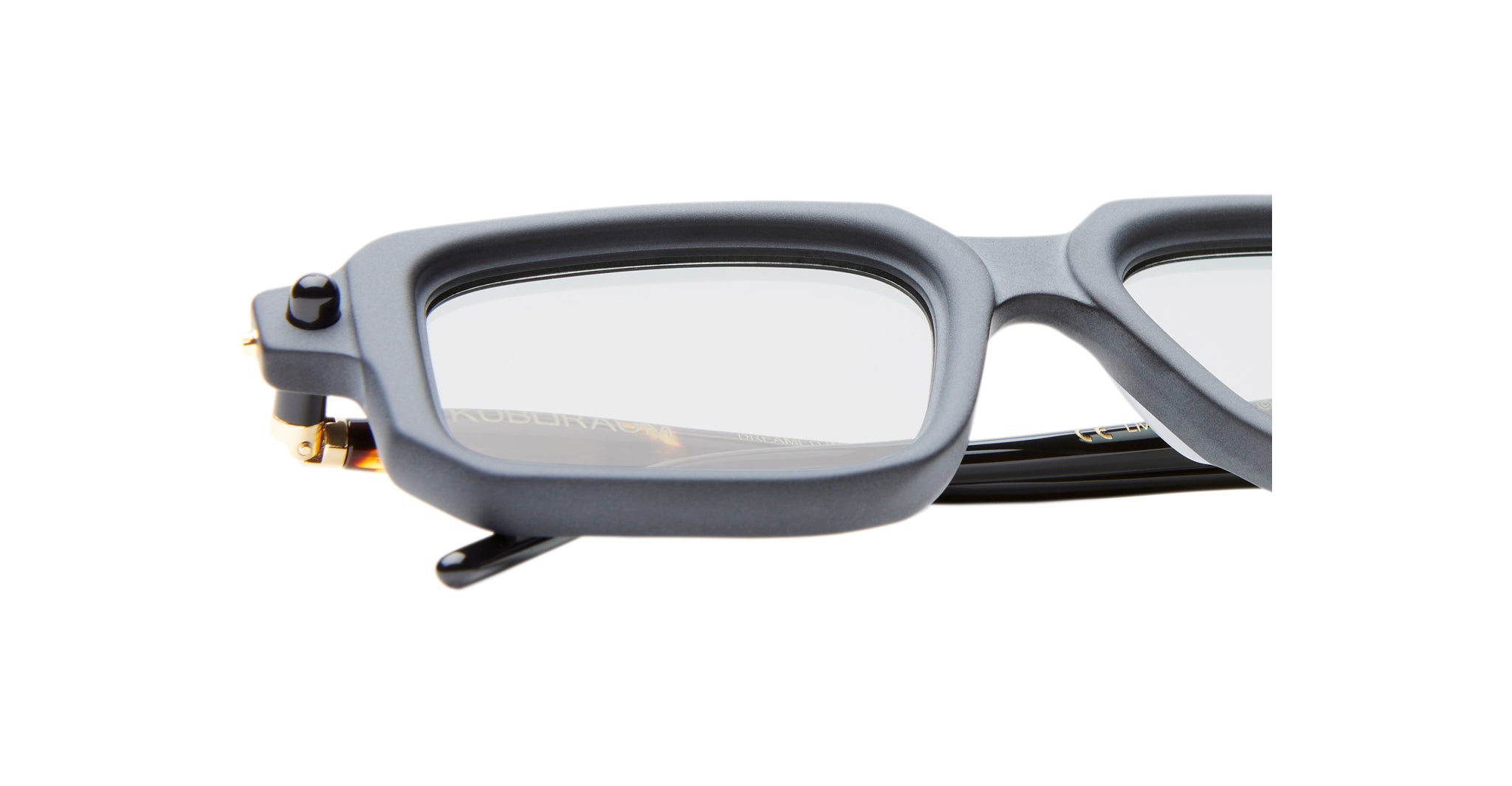 Close-up of the upper half of Kuboraum P23 rectangular eyeglasses, featuring thick matte gray frames, clear lenses, and a visible hinge with part of the black arm on the left.