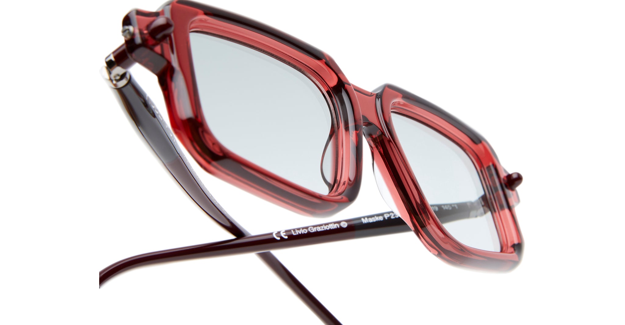 Close-up of Kuboraum P23 eyeglasses featuring red and transparent square frames with thin dark arms, clear lenses, and a glossy finish, displayed on a white background.