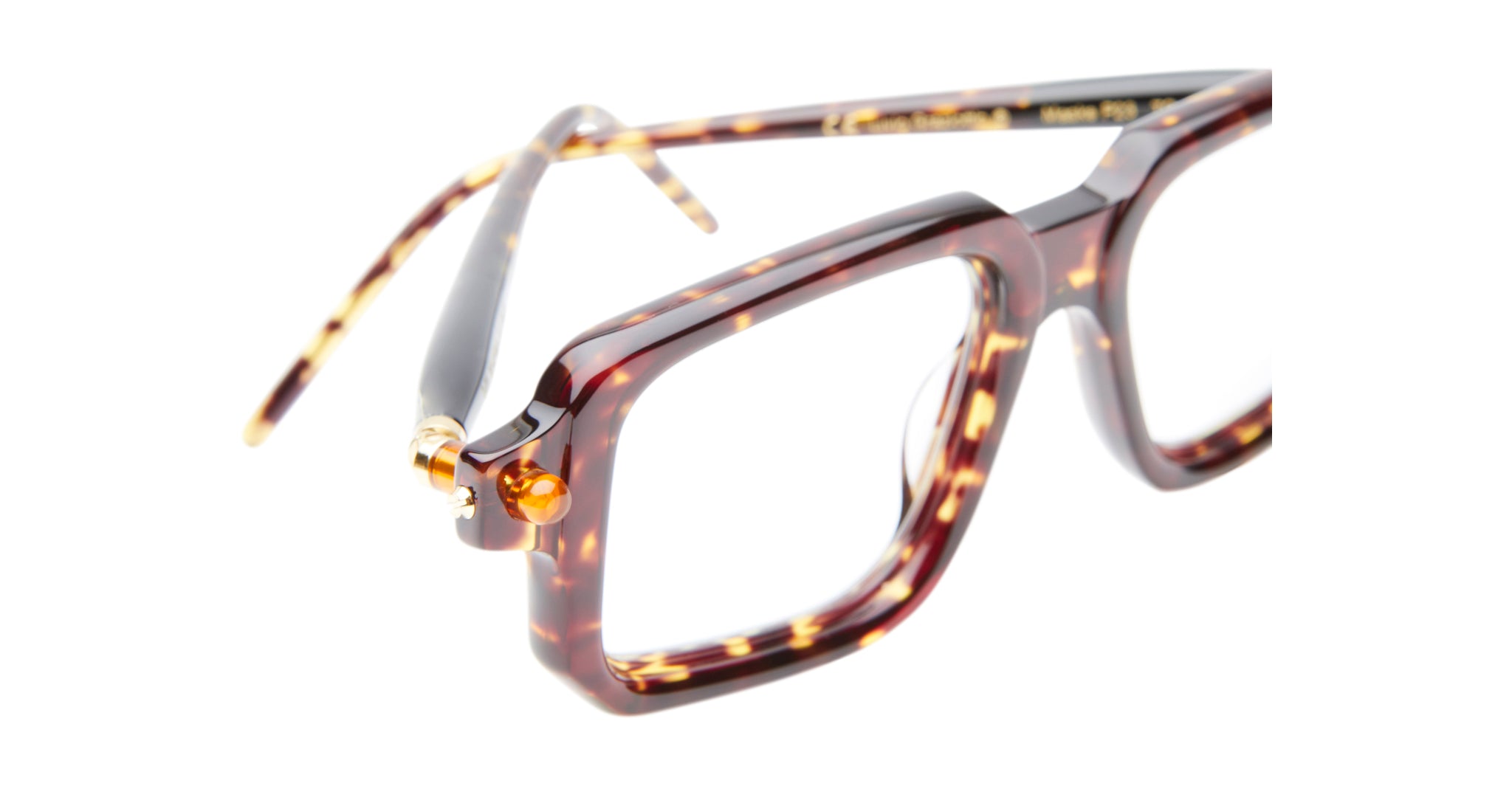 Close-up of Kuboraum P23 tortoiseshell eyeglasses featuring thick rectangular frames and gold hinge accents, set against a white background.