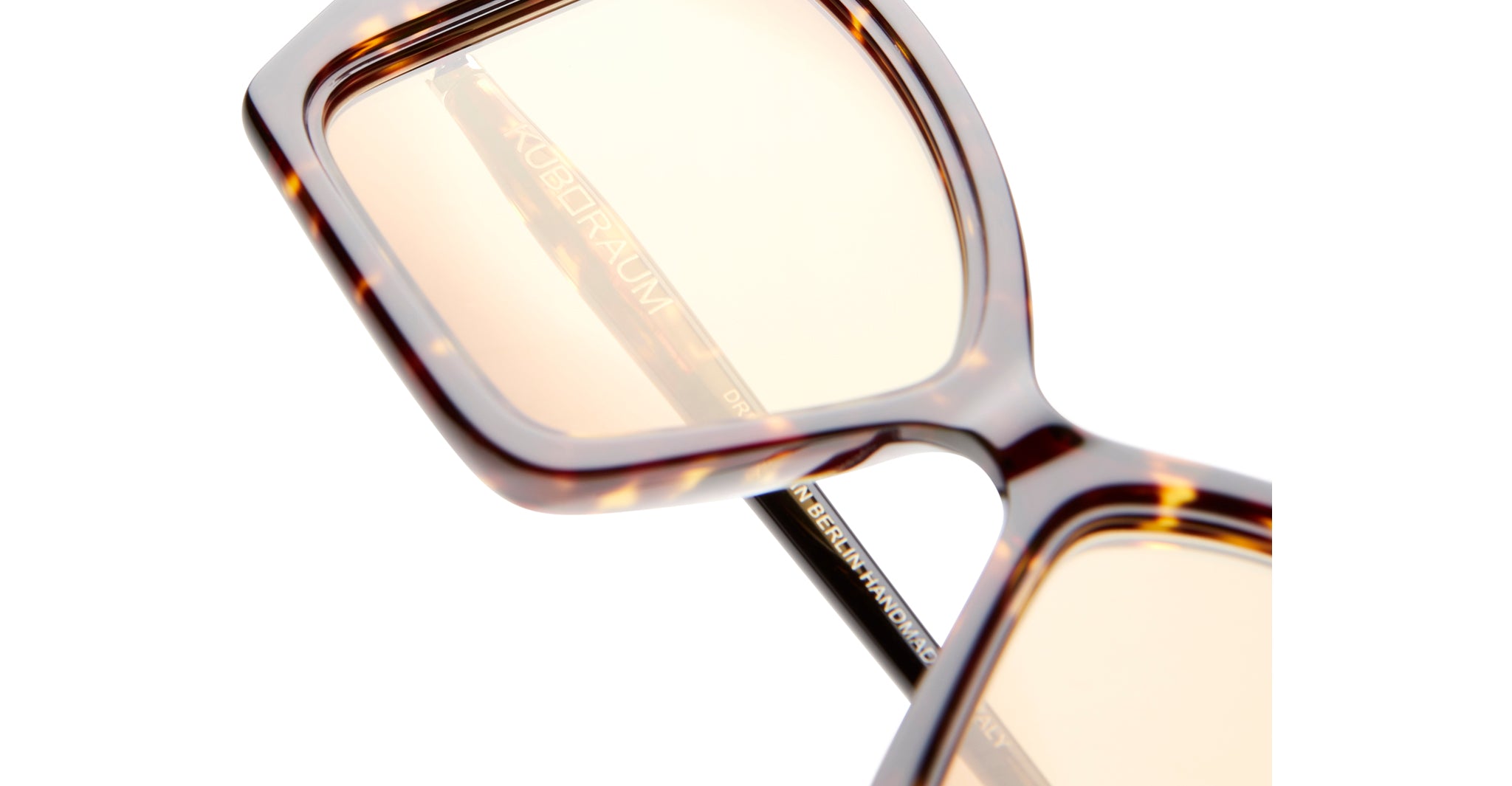 Close-up of Kuboraum P30 tortoiseshell square sunglasses with amber lenses, showing KUBORAUM logo on the temple.