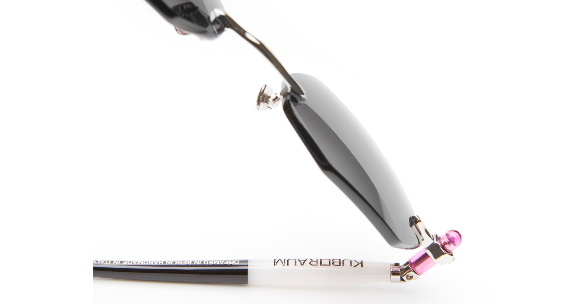 Close-up of Kuboraum P54 designer eyeglasses with black frames, white temples displaying the KUBORAUM logo, metallic hinges, and a pink decorative accent at the temple tips.