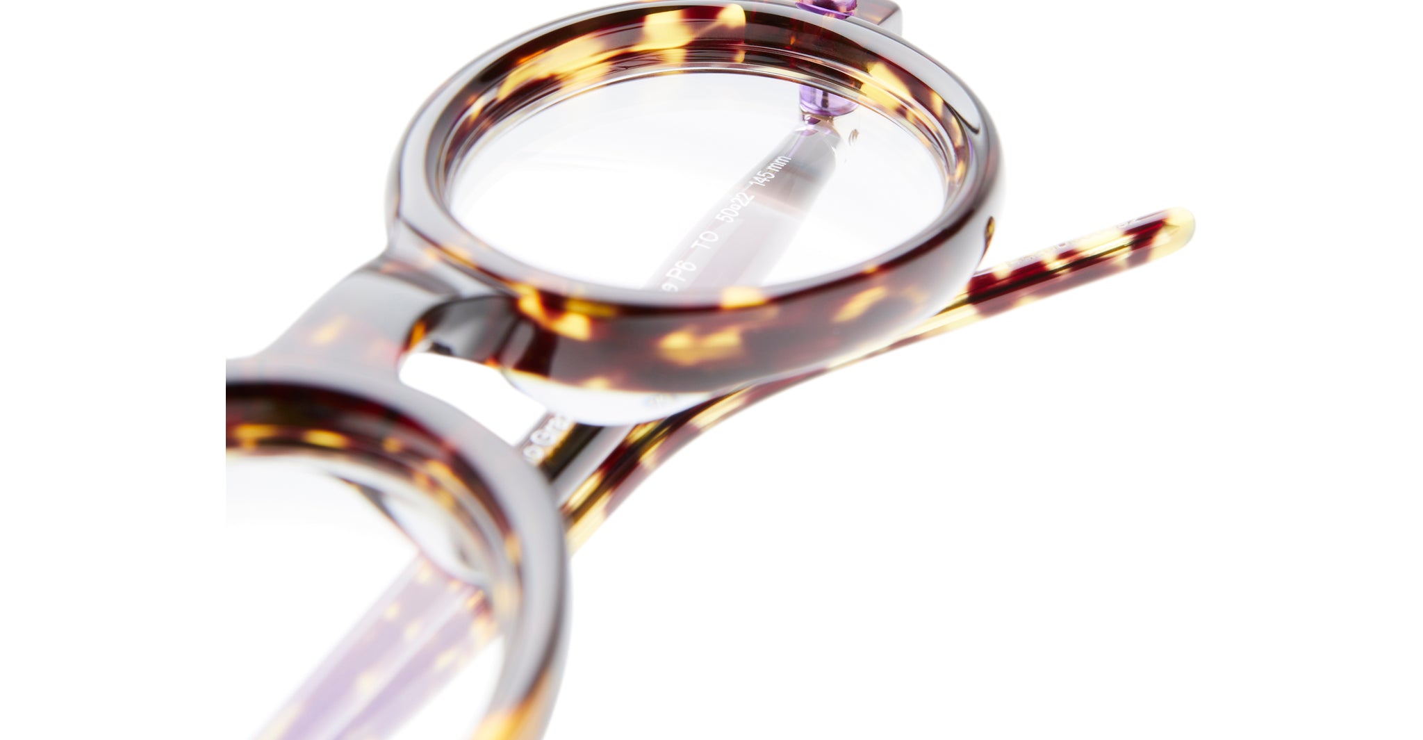 Close-up of Kuboraum P6 round eyeglasses featuring a tortoiseshell pattern with clear lenses and a partial view of the frame and temple set against a white background.