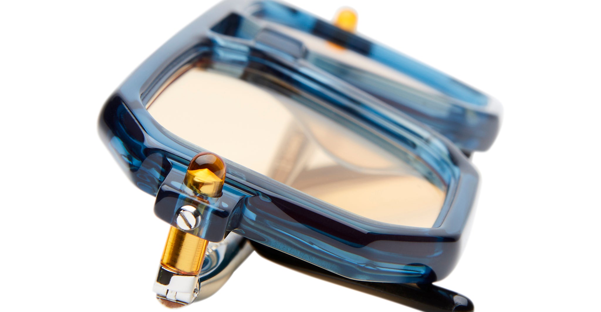 Close-up of Kuboraum P8: modern blue sunglasses with thick, translucent frames and yellow-tinted lenses, shown at an angle to highlight their geometric design and metal hinge detail.