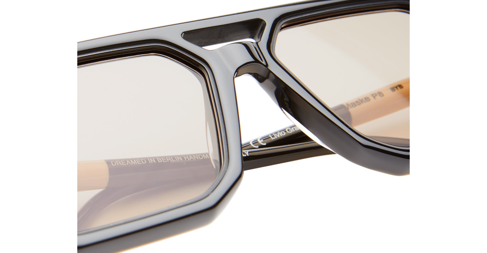 Close-up of Kuboraum P8 black angular eyeglass frames with light lenses, showing DREAMED IN BERLIN HANDMADE on the inside.