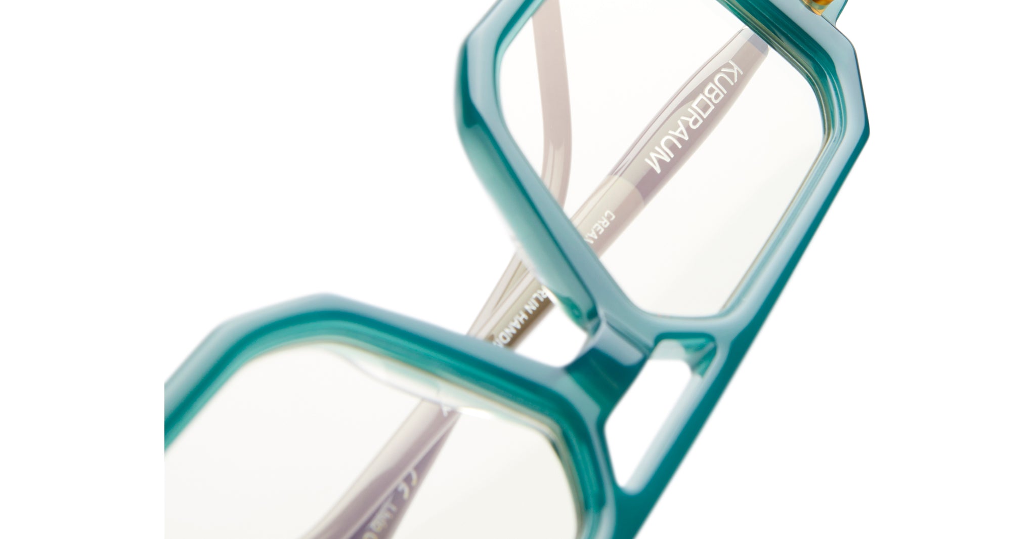 Close-up of Kuboraum P8 teal geometric eyeglasses, clear lenses, lightweight frame, brand name KUBORAUM visible on the arm.