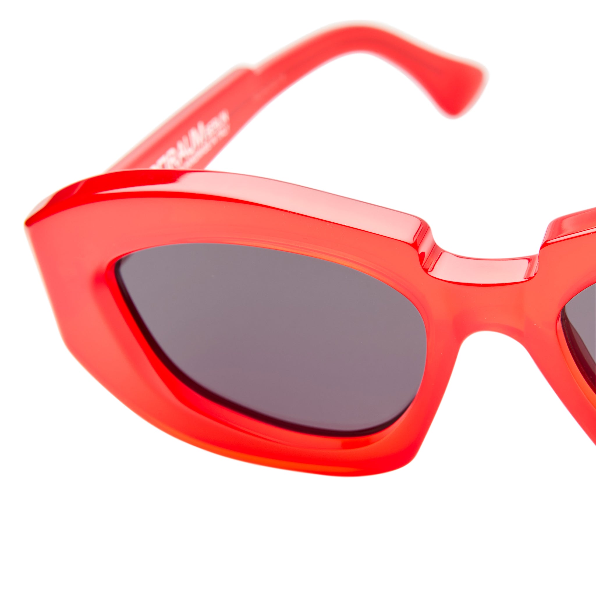 Close-up of the Kuboraum X23 sunglasses featuring bold, thick bright red frames and dark tinted lenses against a white background.