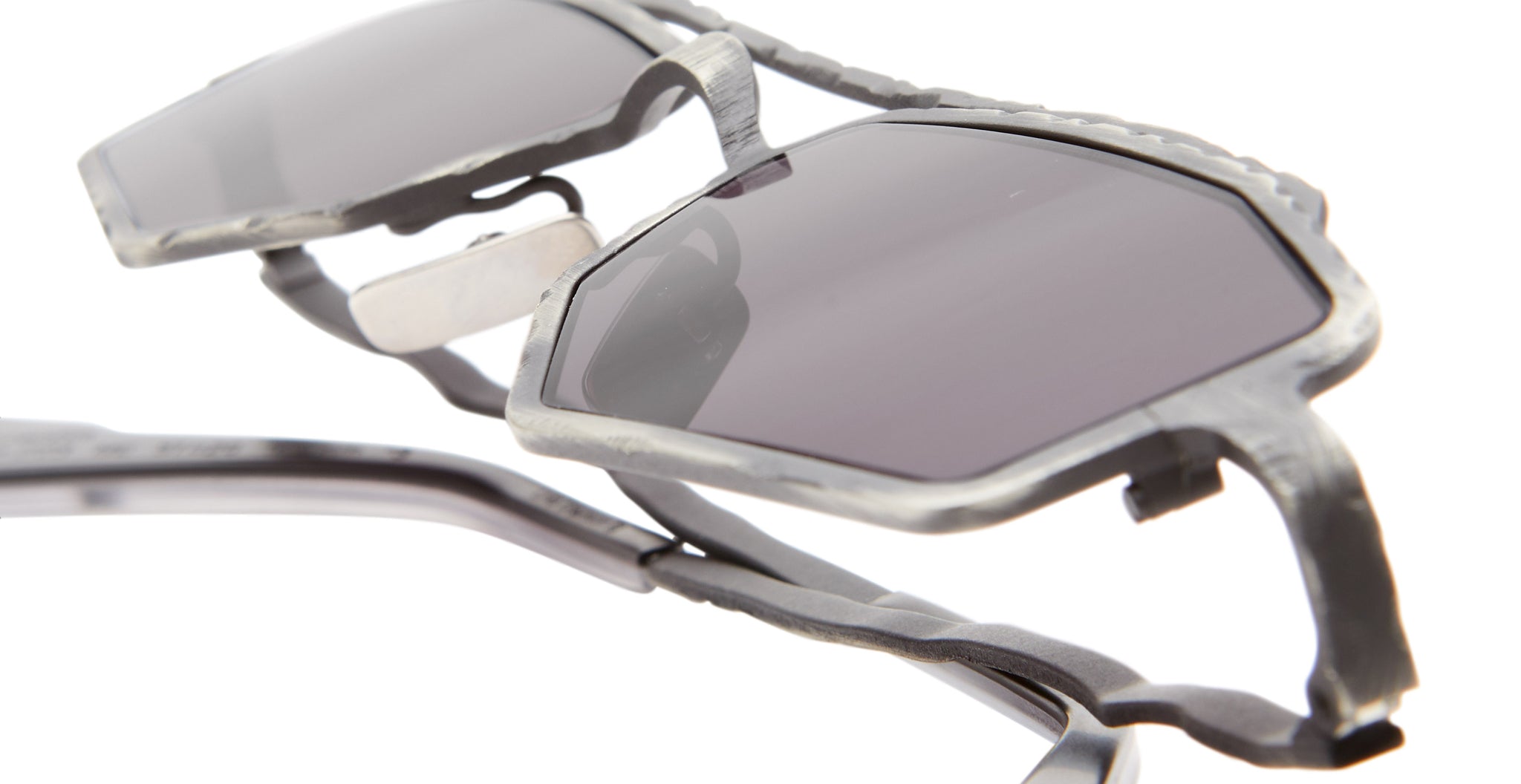 Close-up of Kuboraum Z23 sunglasses featuring geometric silver frames and dark tinted lenses, highlighting their unique angular design and metallic texture against a white background.