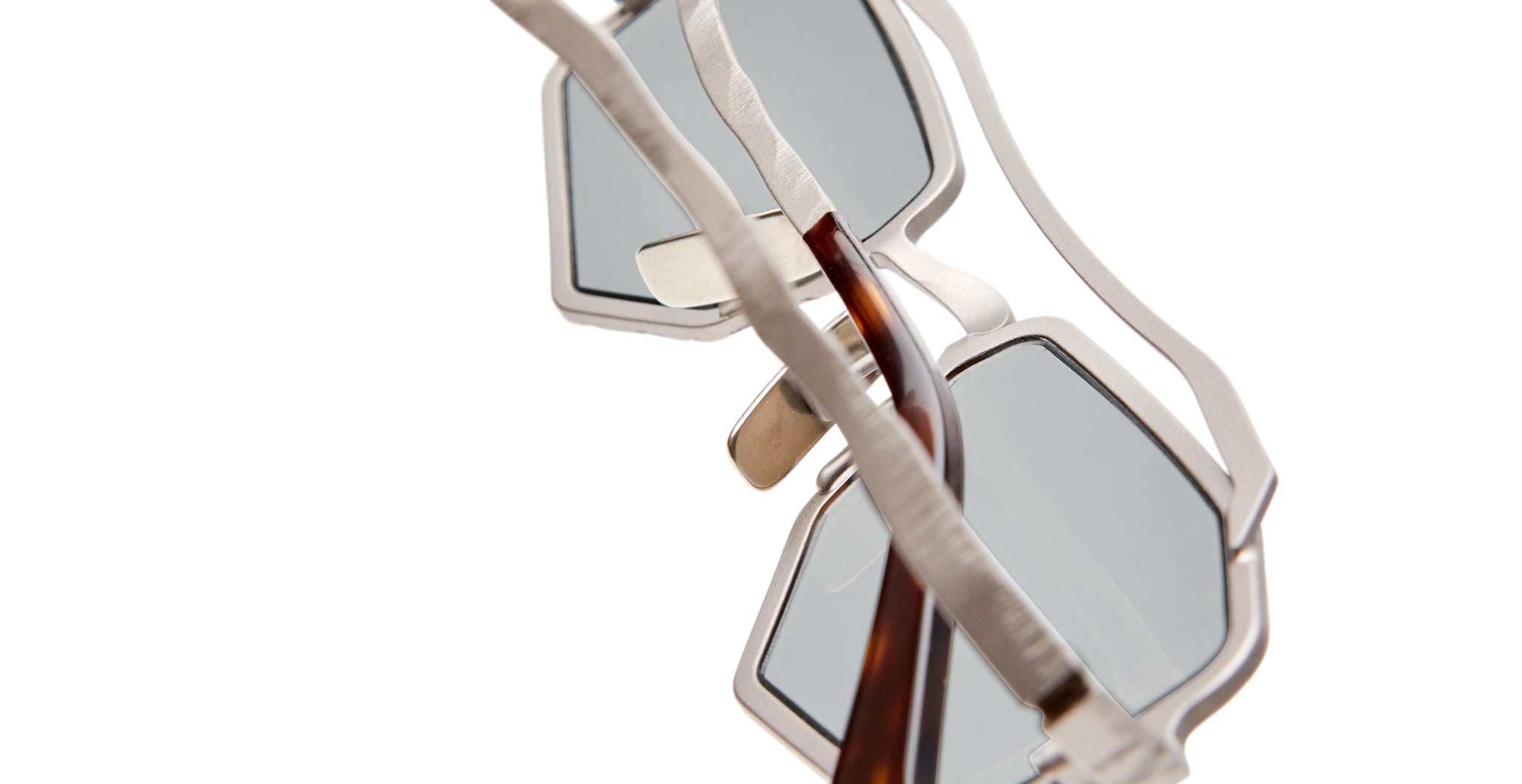 Close-up of Kuboraum Z23 sunglasses featuring modern geometric silver metal frames, light blue-tinted lenses, set against a white background.