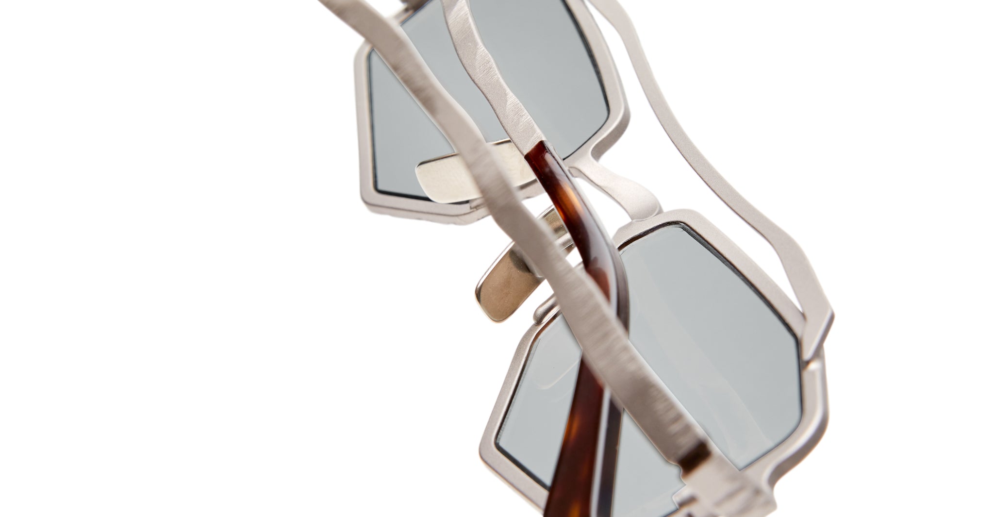 Close-up of Kuboraum Z23 sunglasses featuring modern geometric silver metal frames, light blue-tinted lenses, set against a white background.