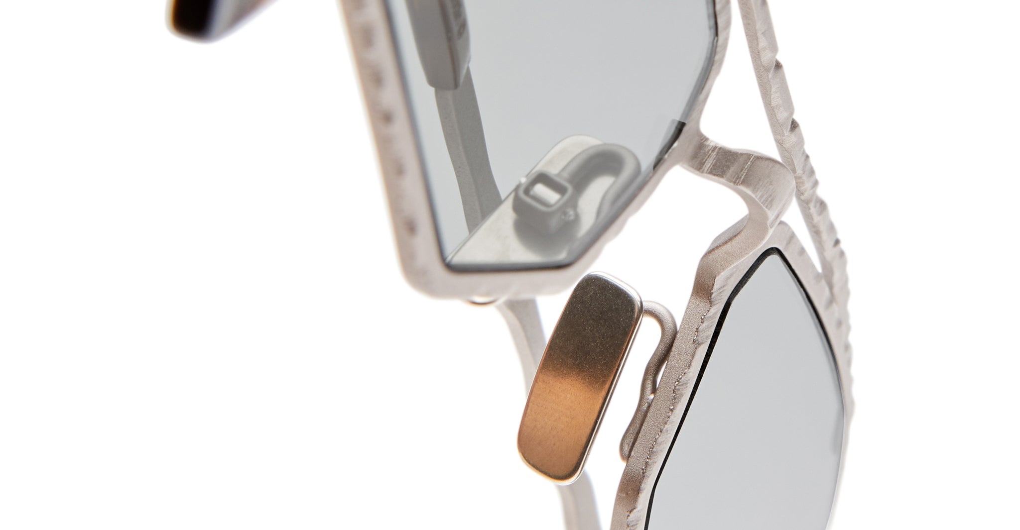 Close-up of Kuboraum Z23 sunglasses featuring silver metal frames, gray tinted lenses, detailed texture, and nose pad on a white background.