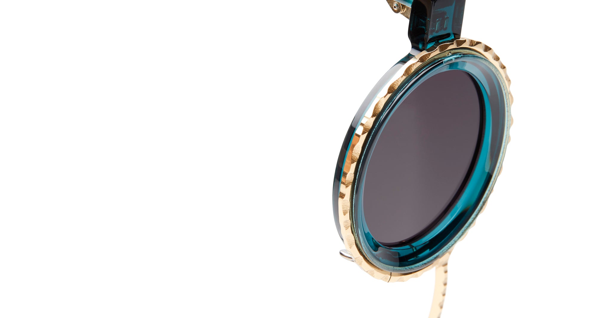 Close-up of Kuboraum Z3 sunglasses lens with round, dark tint and gold and teal rim, viewed from the front.