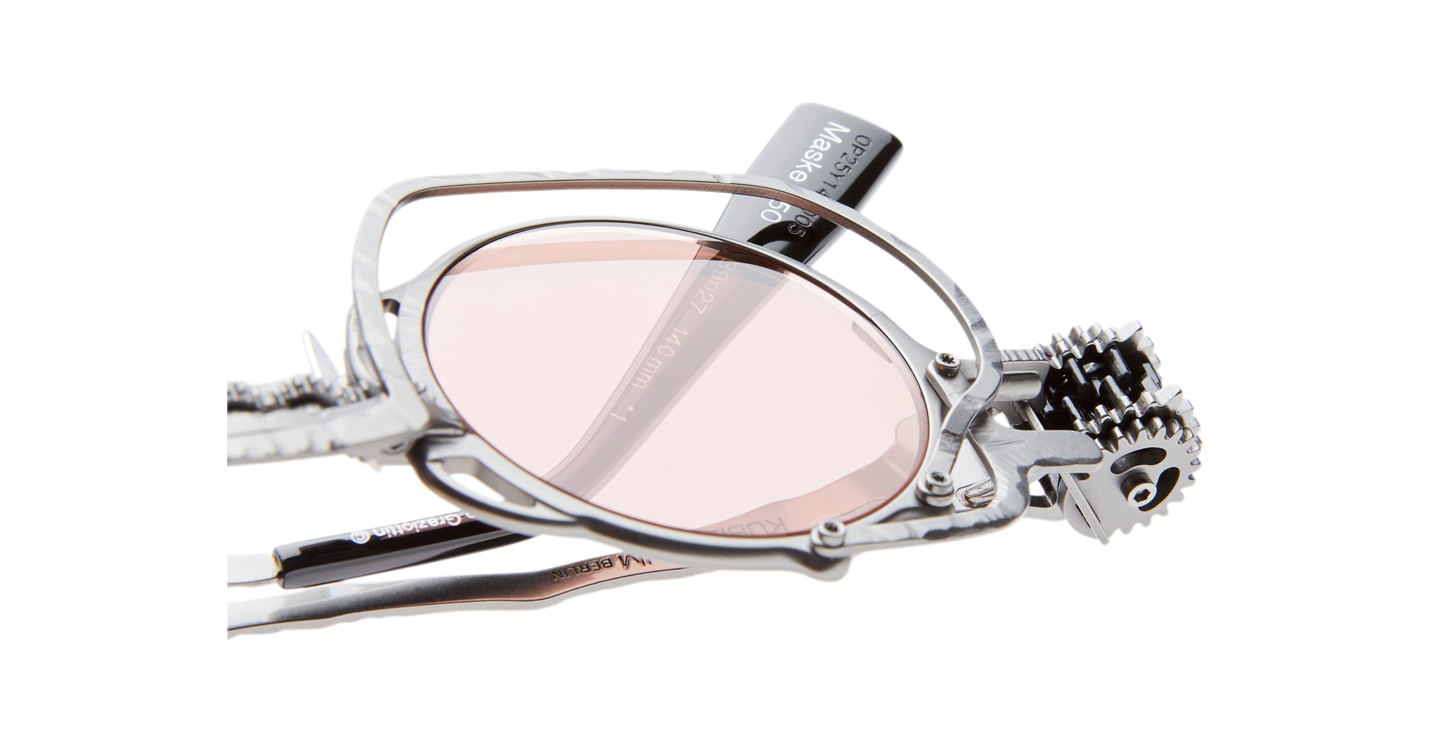 Close-up of Kuboraum Z50 metal steampunk-style eyeglasses with pink-tinted lenses, featuring intricate gears and mechanical details near the frames, and Kuboraum branding on the temple.