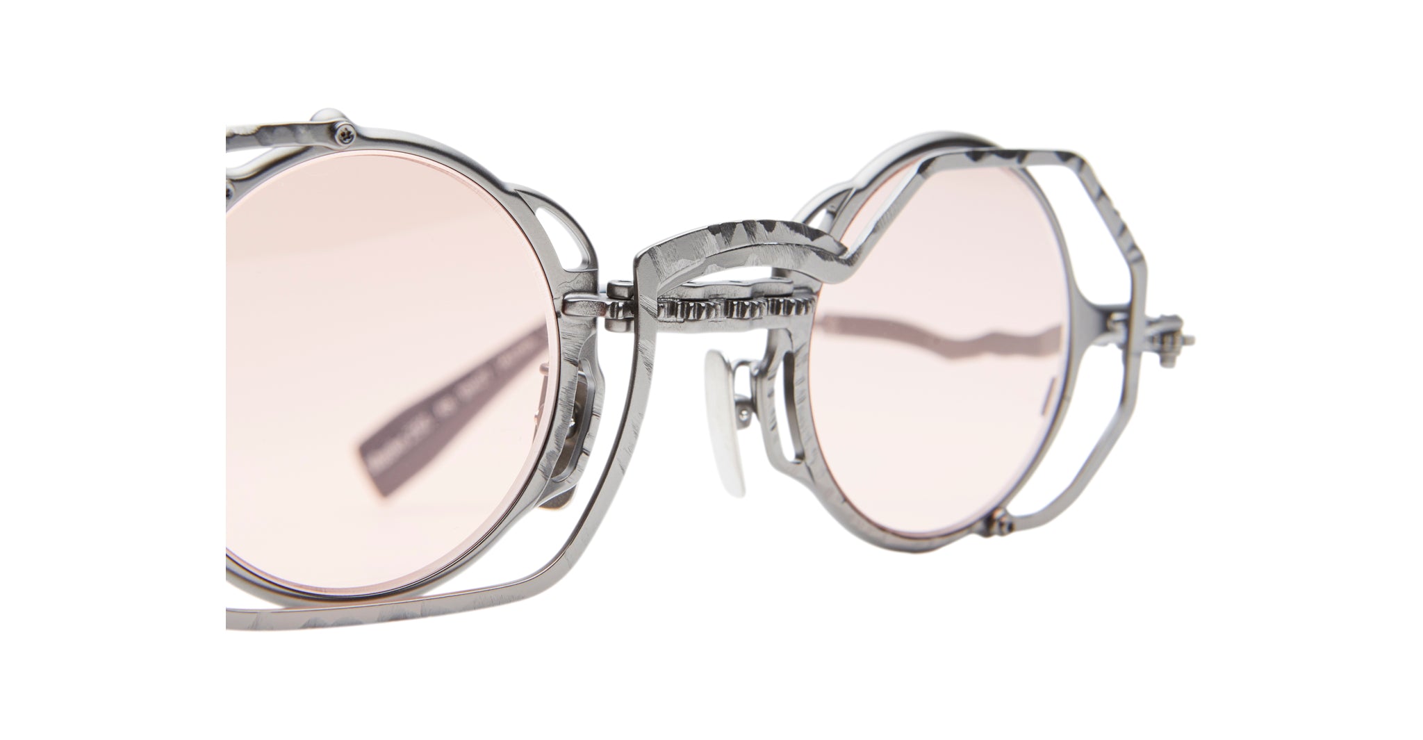 Close-up view of the Kuboraum Z50, featuring stylish round sunglasses with light pink lenses and a unique, intricate silver metal frame, shown against a white background.