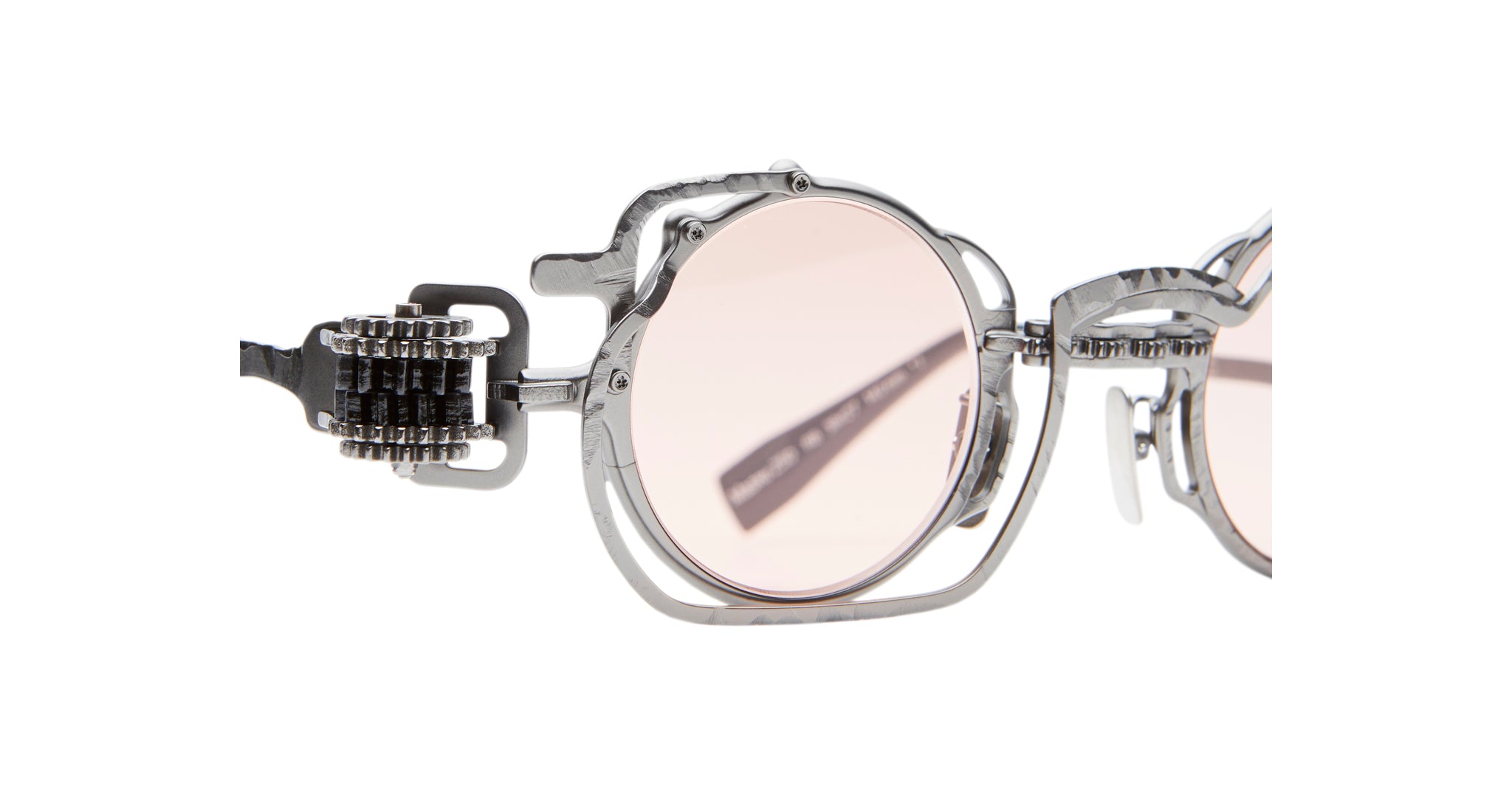 Close-up of Kuboraum Z50 eyeglasses: round frames with light pink lenses and distinctive metallic temples adorned with intricate, gear-inspired details.