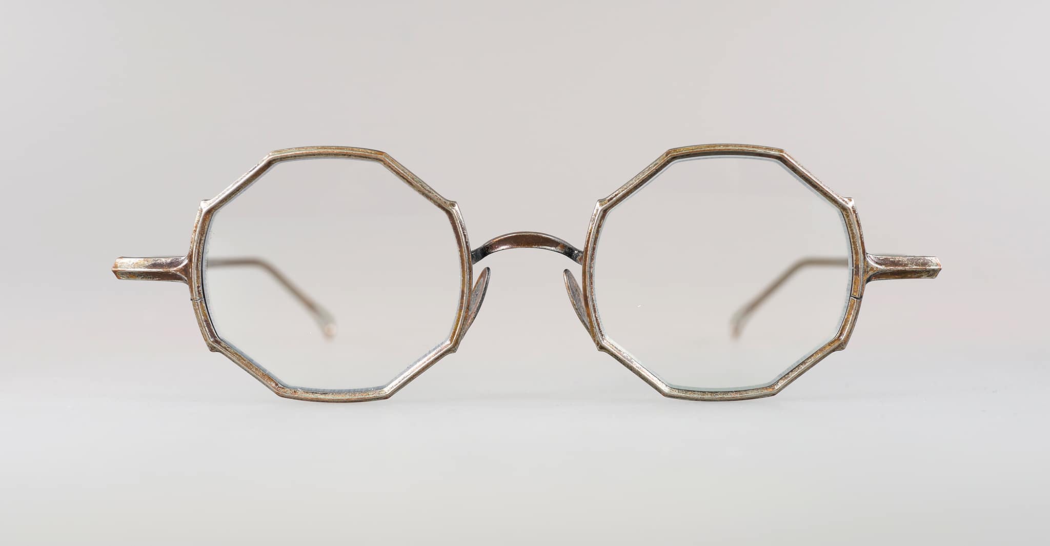A pair of vintage eyeglasses with thin metal frames and octagonal lenses, viewed from the front against a plain, light background.