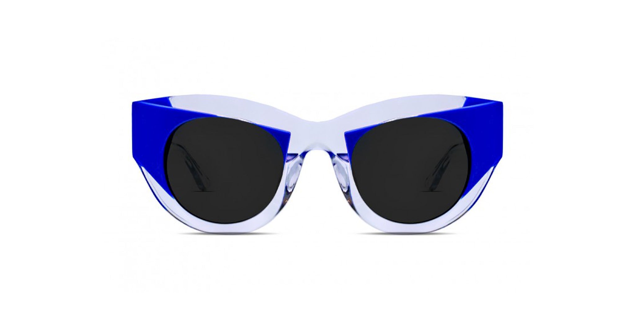 The Thierry Lasry Captivity features thick, angular blue and white frames and large, round black lenses, shown on a white background.