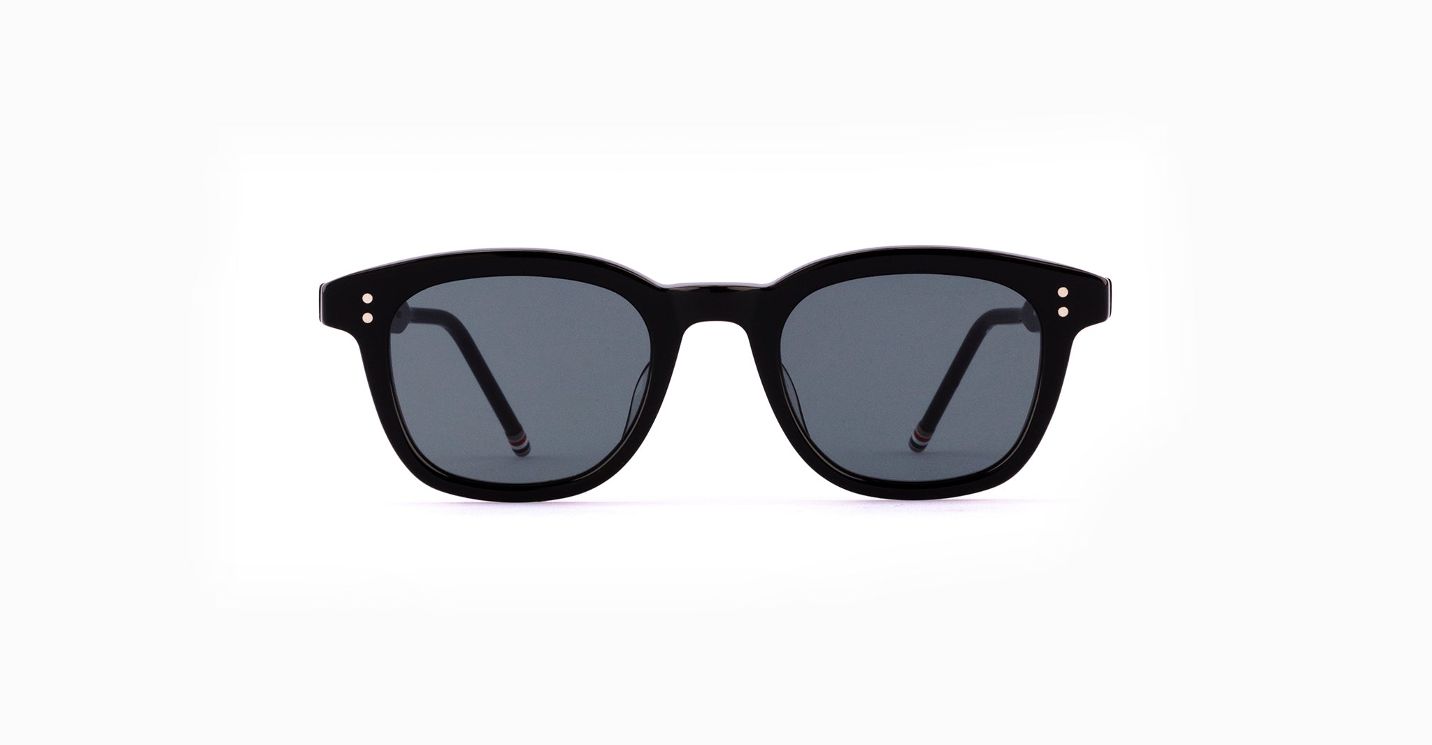 A pair of Thom Browne 921 Sunglasses in Black with dark lenses is shown against a plain white background, viewed from the front with the temples extended backward.