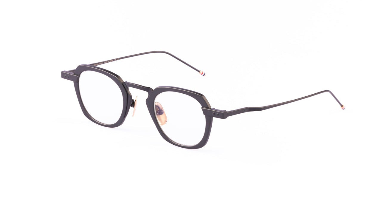 The Thom Browne 930 features black, rectangular eyeglasses with thin arms and clear lenses, shown on a white background.