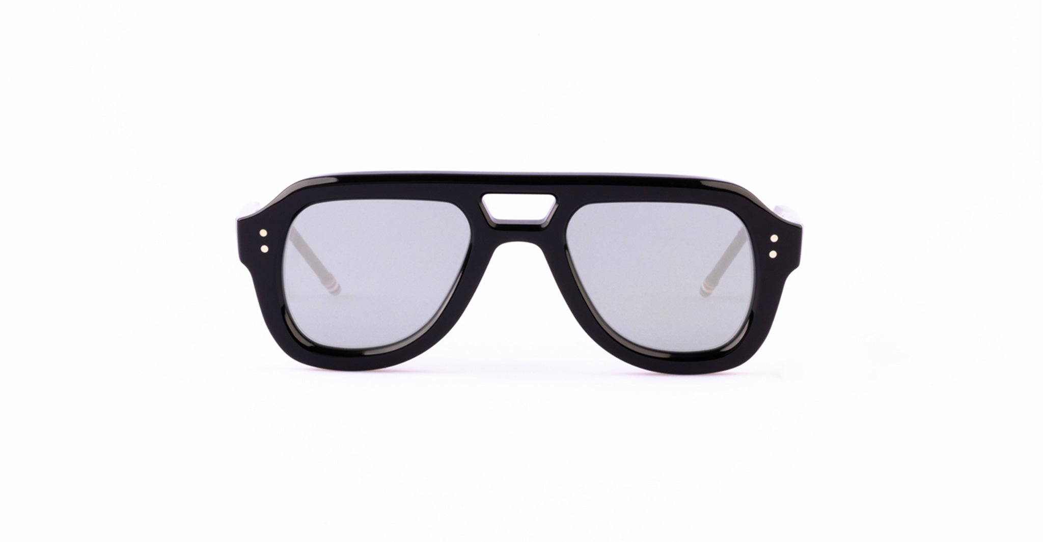 Black, thick-rimmed Thom Browne sunglasses with gray lenses and a flat top design.